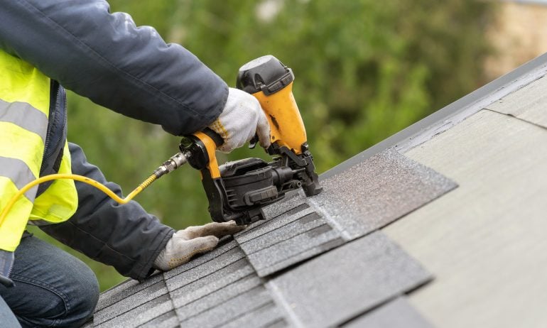 Contractor installing roof shingles with a nail gun for Truhome LLC PA home improvement services.