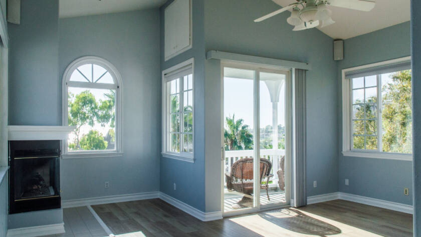 Bright and spacious living room with large windows and sliding glass doors, showcasing the results of expert home improvement services that enhance natural light and open space.