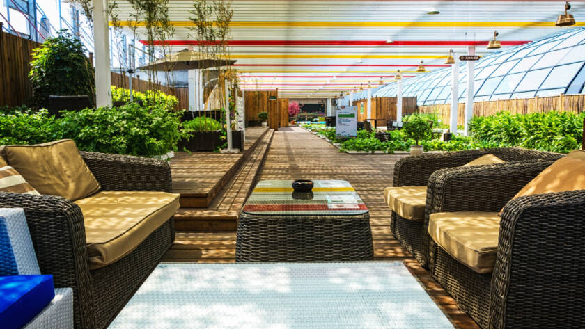 Modern outdoor patio with stylish wicker furniture, greenery, and shaded roofing, showcasing results of professional home improvement services.