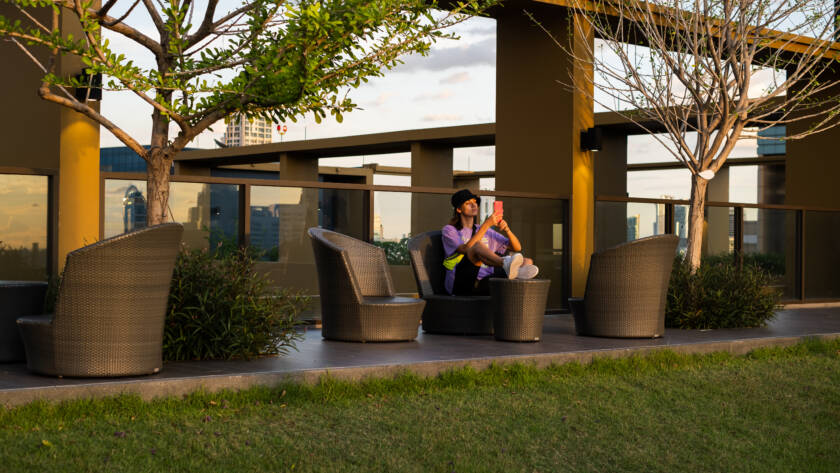 A person sitting on a modern outdoor patio with wicker furniture and greenery, enjoying the space enhanced by professional home improvement services.